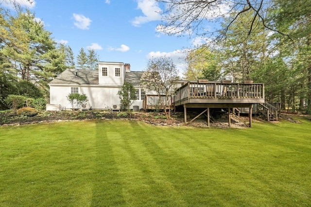 back of property featuring a deck, a lawn, and stairs