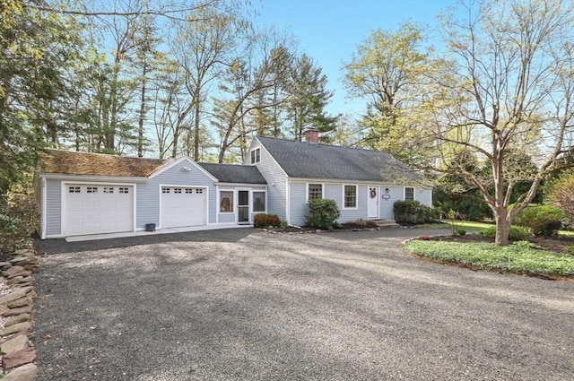 view of front of house with a garage, driveway, and a chimney