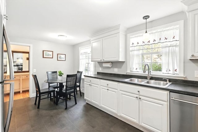 kitchen featuring dishwasher, a sink, dark countertops, and plenty of natural light
