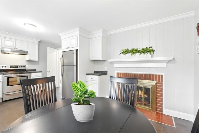 dining space featuring a brick fireplace, dark tile patterned flooring, crown molding, and baseboards