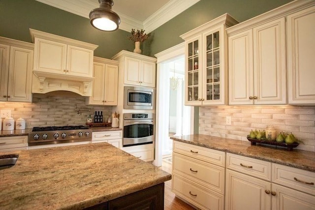 99 Elizabeth St, Agawam, MA 01030 - kitchen featuring appliances with stainless steel finishes, tasteful backsplash, cream cabinetry, light stone counters, and glass insert cabinets