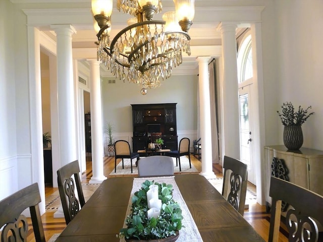 99 Elizabeth St, Agawam, MA 01030 - dining area with ornate columns, a decorative wall, wainscoting, crown molding, and wood finished floors