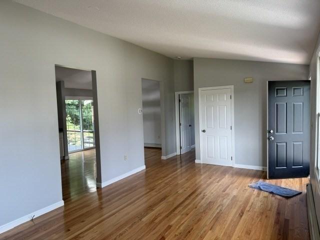 empty room featuring light wood-type flooring, baseboard heating, and plenty of natural light