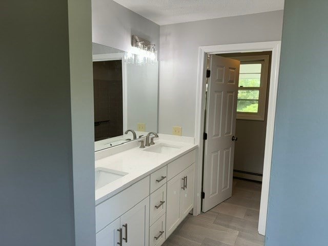 bathroom with vanity, a textured ceiling, a baseboard heating unit, and hardwood / wood-style floors