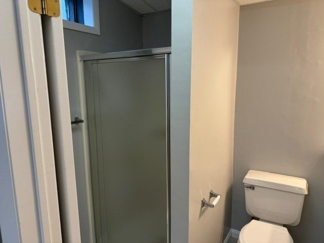 bathroom with a shower with door and toilet