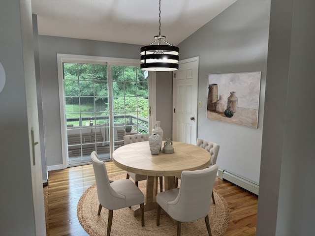 dining area featuring vaulted ceiling, a notable chandelier, a baseboard radiator, and light wood-type flooring