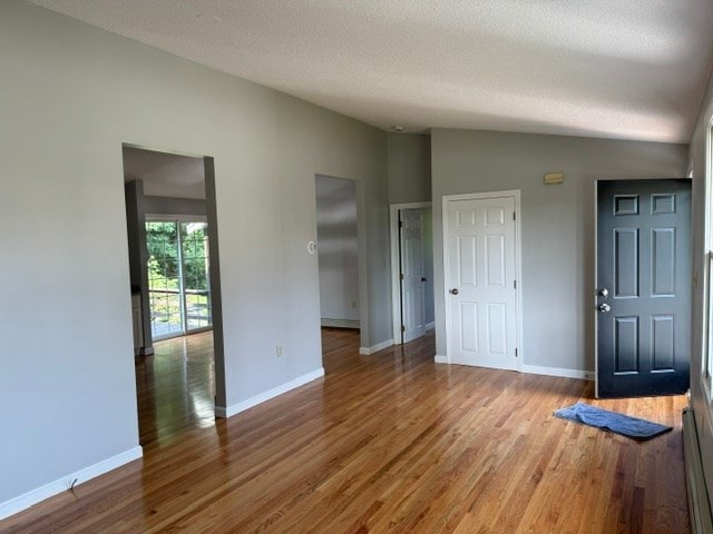 interior space featuring hardwood / wood-style floors, vaulted ceiling, and a textured ceiling