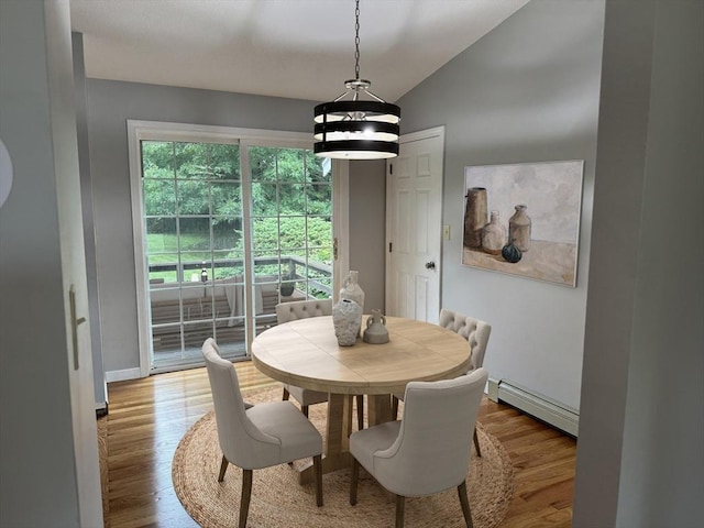 dining area featuring vaulted ceiling, a baseboard heating unit, and light hardwood / wood-style floors