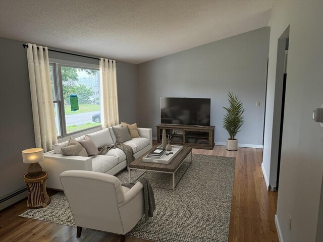 unfurnished room with light hardwood / wood-style floors, a textured ceiling, and a baseboard heating unit