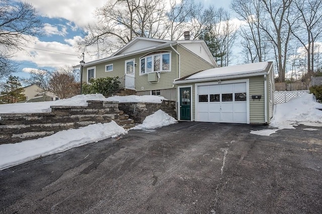 view of front of home featuring aphalt driveway, a chimney, and an attached garage