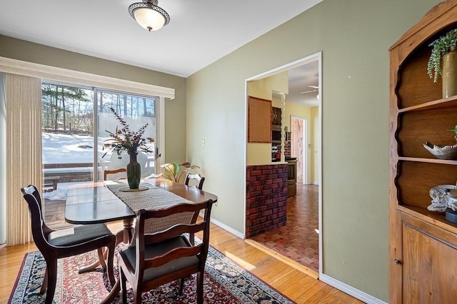 dining room featuring light wood-type flooring, baseboards, and lofted ceiling