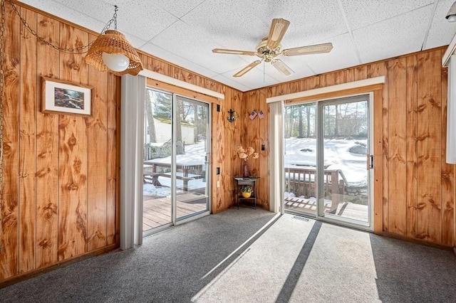 entryway with wood walls, carpet, and a ceiling fan