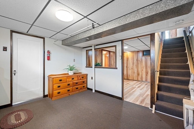 finished basement with a paneled ceiling, baseboards, and stairs