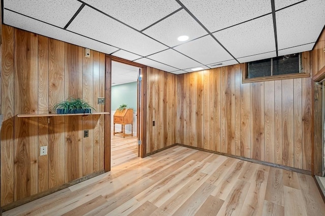 interior space featuring light wood-type flooring, wood walls, visible vents, and a paneled ceiling