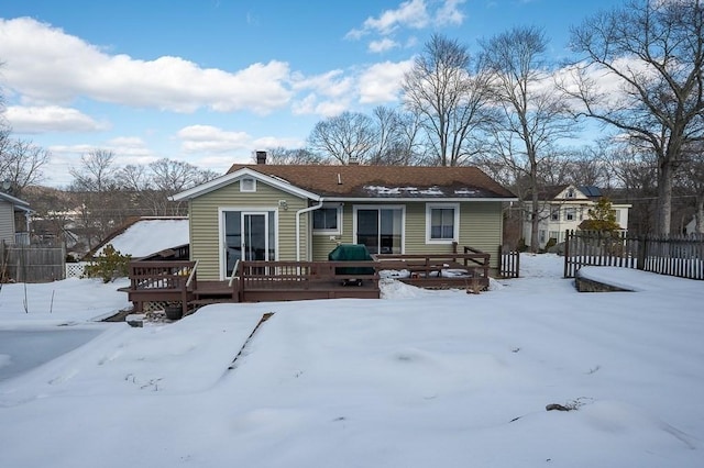 snow covered rear of property featuring fence and a wooden deck