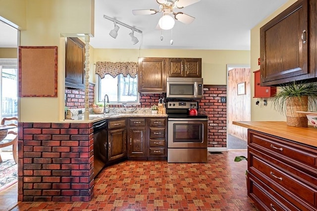 kitchen featuring light countertops, decorative backsplash, appliances with stainless steel finishes, a ceiling fan, and a sink