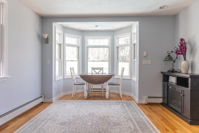 dining room with light wood-style floors, a baseboard radiator, and baseboards