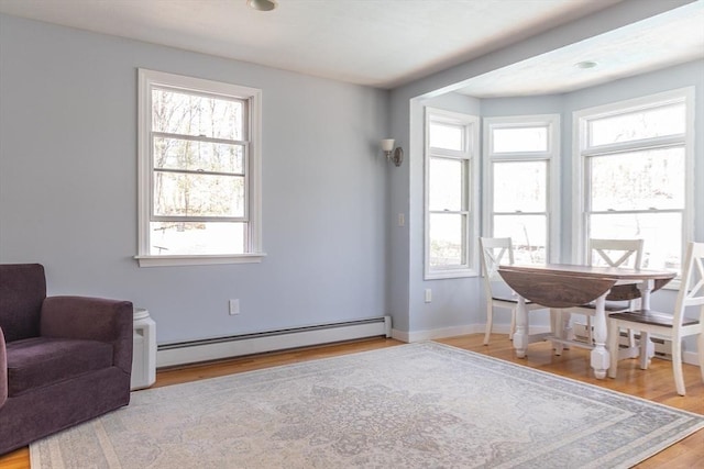 sitting room featuring baseboards, a baseboard heating unit, and light wood-type flooring