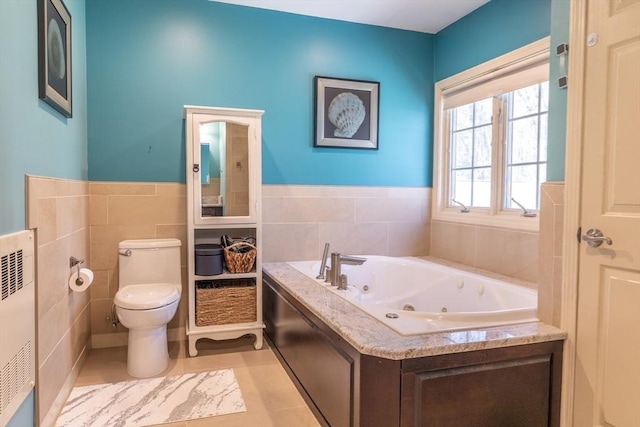 bathroom featuring wainscoting, toilet, a heating unit, tile walls, and a tub with jets