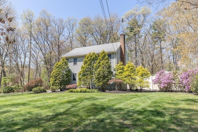 view of side of home with a yard and a chimney