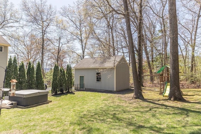 view of yard with a hot tub, an outdoor structure, a playground, and a shed