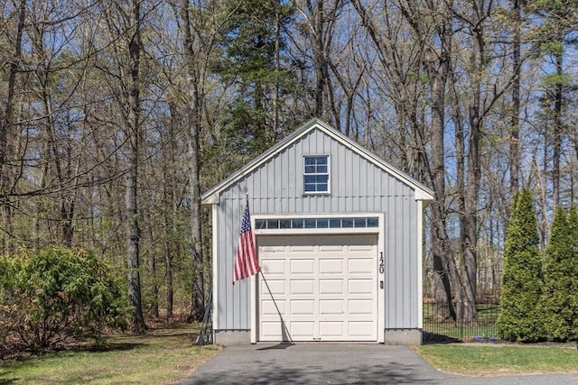 detached garage featuring fence and aphalt driveway