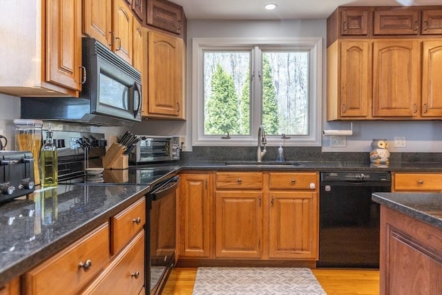 kitchen featuring a sink, brown cabinetry, dark stone counters, a toaster, and black appliances