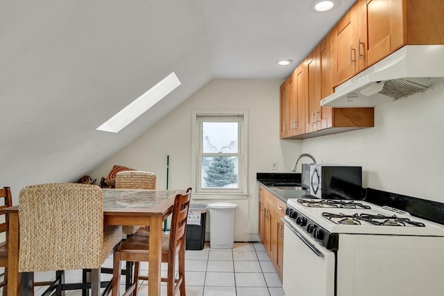 kitchen with sink, white gas stove, light tile patterned flooring, and vaulted ceiling with skylight