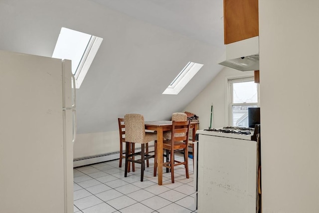 dining room featuring baseboard heating, lofted ceiling with skylight, and light tile patterned floors