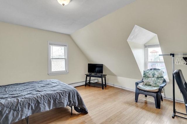 bedroom featuring light wood-type flooring, baseboard heating, and vaulted ceiling