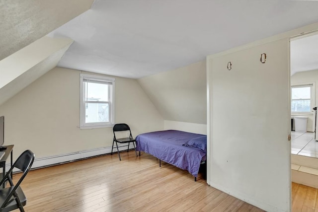 bedroom featuring multiple windows, light wood-type flooring, vaulted ceiling, and baseboard heating