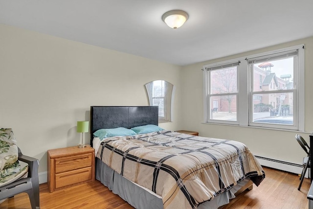 bedroom with a baseboard radiator and light hardwood / wood-style flooring