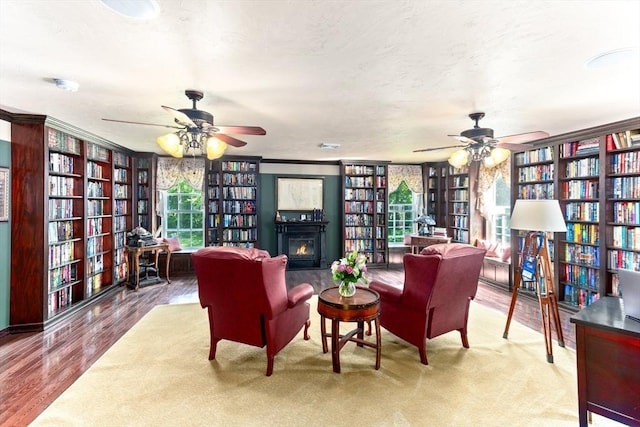 31 Swing Dr, Berkley, MA 02779 - living area featuring wall of books, a ceiling fan, and a warm lit fireplace