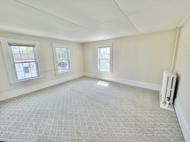 empty room featuring radiator, baseboards, and carpet flooring