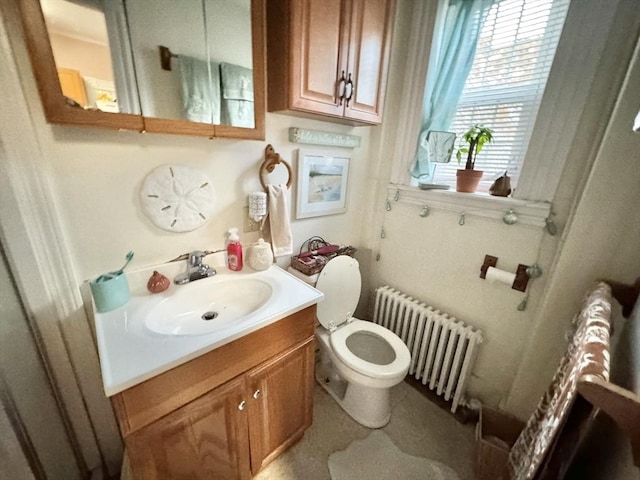 half bath featuring vanity, toilet, and radiator