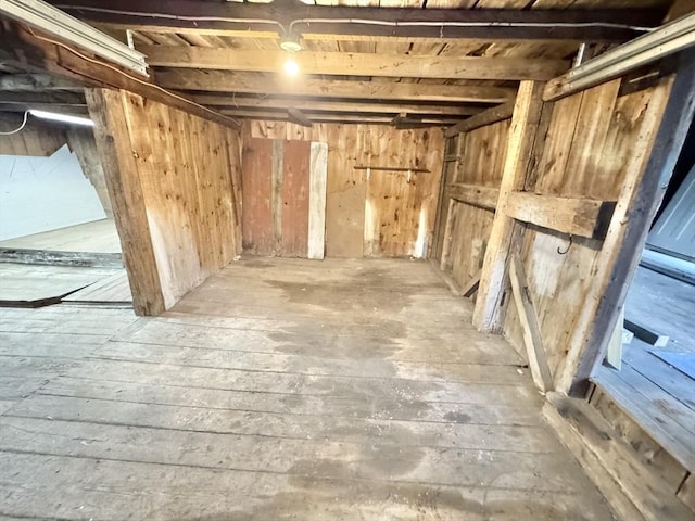 unfinished below grade area featuring hardwood / wood-style flooring and wooden walls