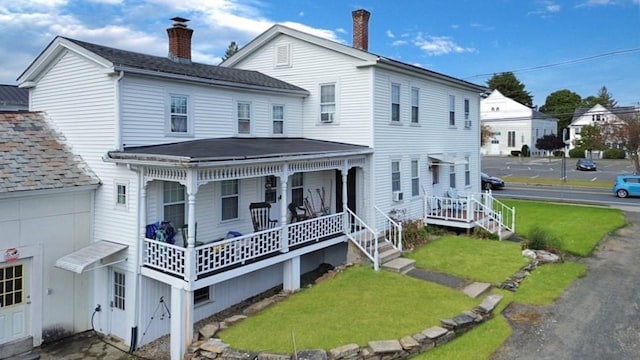 back of house with a yard, a porch, and a chimney