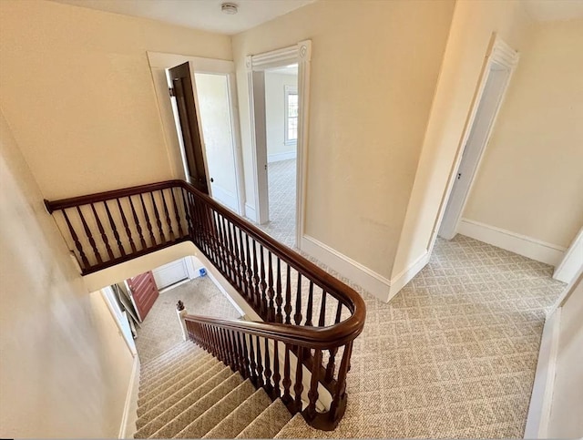 stairway with baseboards and carpet flooring