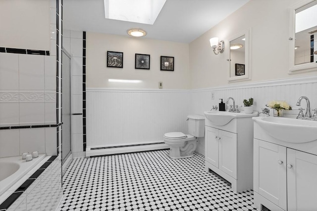 8 Winthrop Ave, Bedford, MA 01730 - bathroom with a baseboard heating unit, a wainscoted wall, two vanities, tiled shower, and a skylight