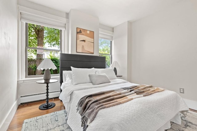 48 Kent St Unit 1, Brookline, MA 02445 - bedroom featuring a baseboard heating unit, wood finished floors, and baseboards