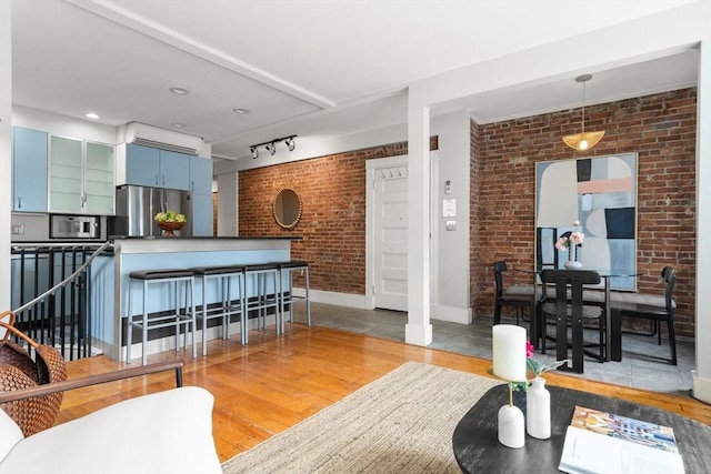 48 Kent St Unit 1, Brookline, MA 02445 - living area with brick wall, light wood-style flooring, baseboards, and rail lighting