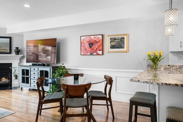 100 Burrill St Unit 3, Swampscott, MA 01907 - dining room featuring crown molding, light wood finished floors, a fireplace with flush hearth, a wainscoted wall, and a decorative wall