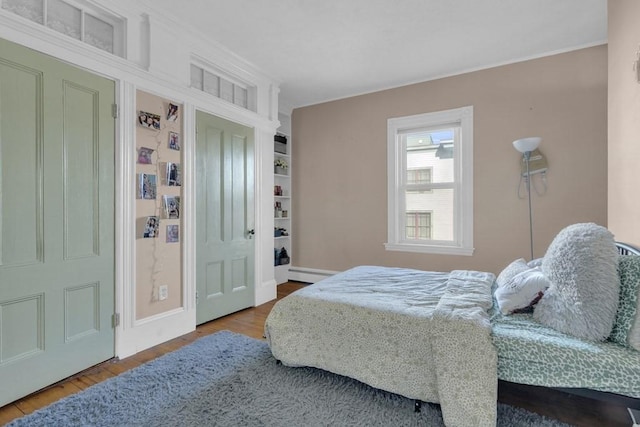 201 High St, Brookline, MA 02445 - bedroom featuring a baseboard heating unit, baseboards, wood finished floors, and crown molding