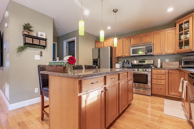 578-580 Detroit St, Fall River, MA 02721 - kitchen featuring appliances with stainless steel finishes, a kitchen breakfast bar, light wood-style flooring, a kitchen island, and dark stone countertops