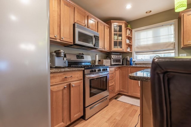 578-580 Detroit St, Fall River, MA 02721 - kitchen with appliances with stainless steel finishes, light wood-style floors, dark stone countertops, glass insert cabinets, and open shelves