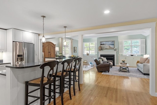 62 Waite Rd, Boxborough, MA 01719 - kitchen with stainless steel fridge, a breakfast bar, dark countertops, open floor plan, and light wood finished floors