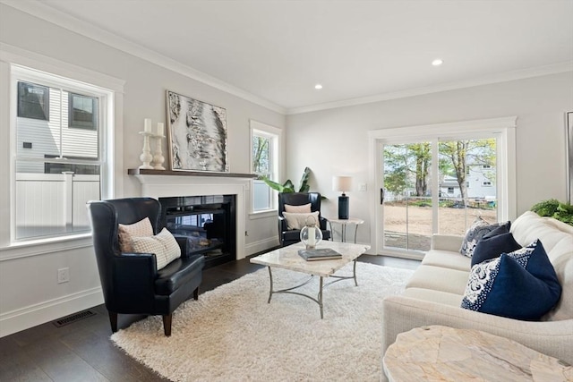 living area featuring a glass covered fireplace, a wealth of natural light, visible vents, and wood finished floors