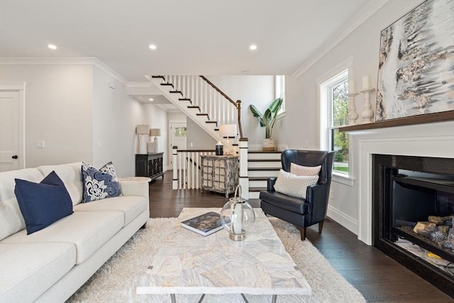 living area with wood finished floors, stairway, a glass covered fireplace, ornamental molding, and recessed lighting