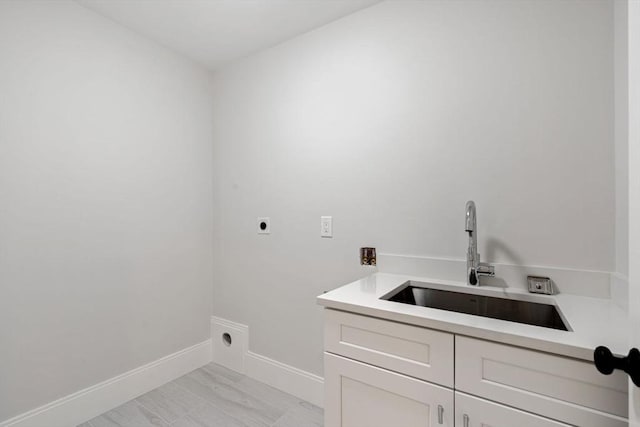 clothes washing area featuring cabinet space, washer hookup, a sink, electric dryer hookup, and baseboards