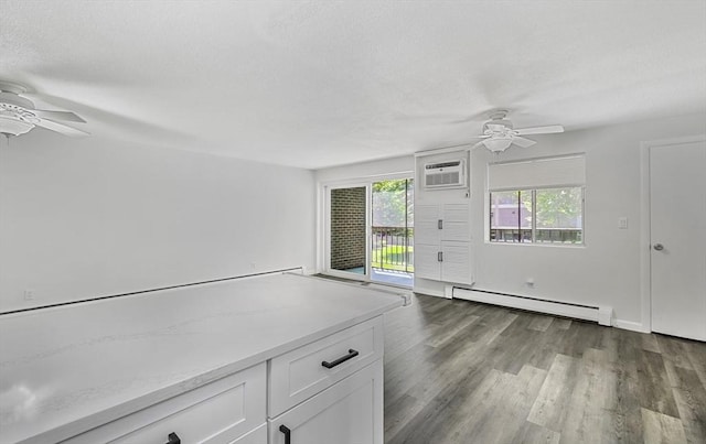 64 Main St Unit 25B, Stoneham, MA 02180 - unfurnished living room with ceiling fan, baseboard heating, wood finished floors, a textured ceiling, and a wall mounted air conditioner